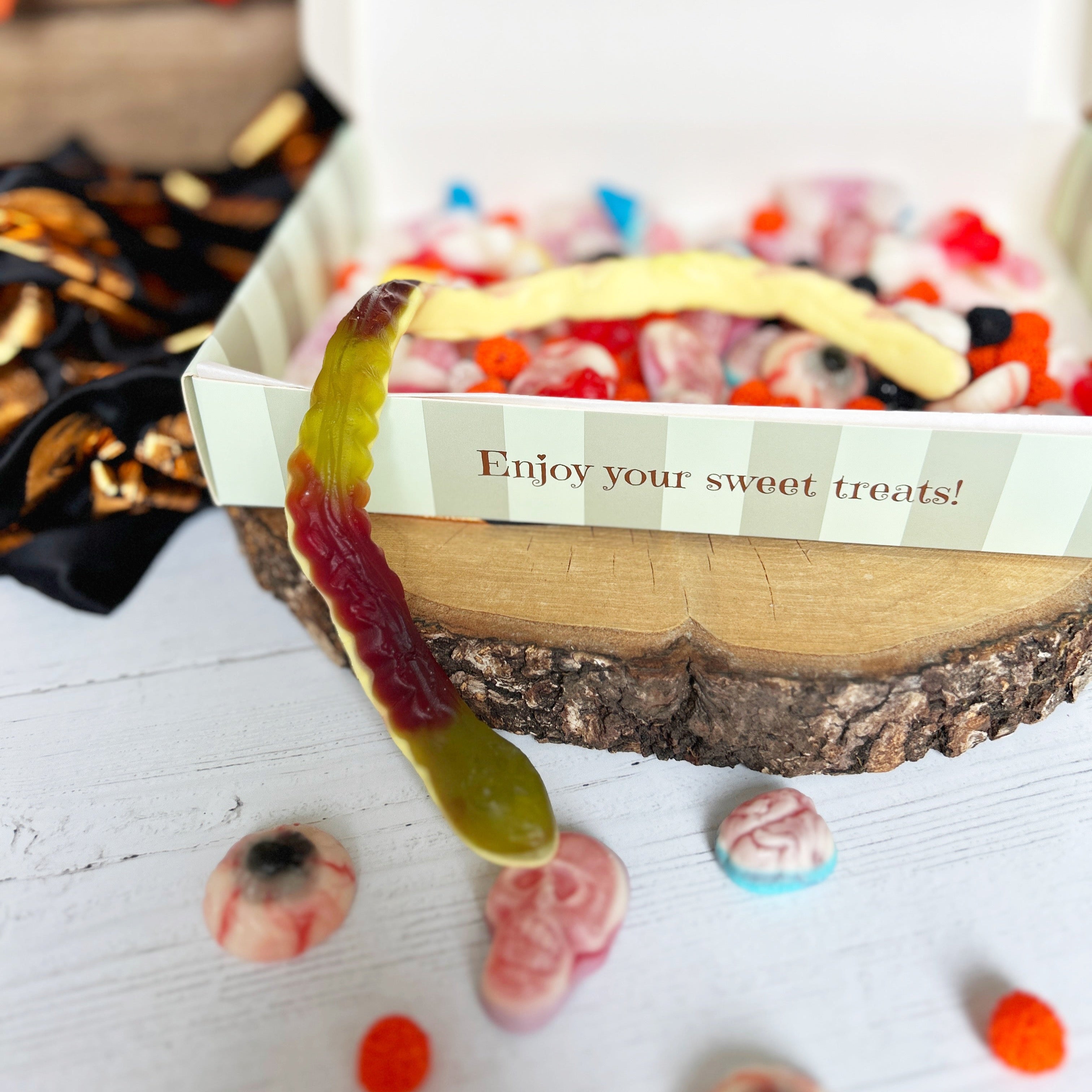 Decorative candy dish with colorful candies and a banana, placed on a wooden surface.