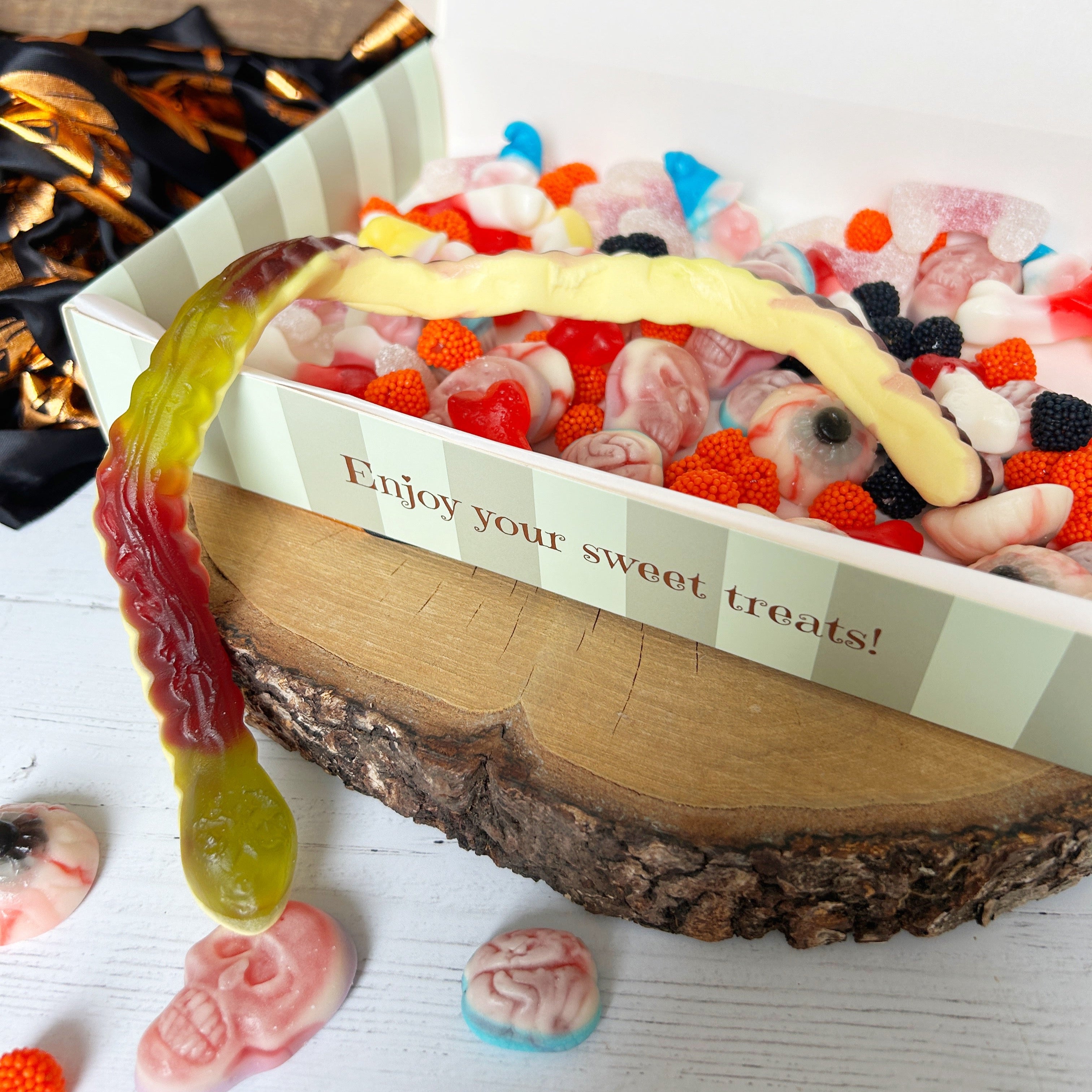 Box of colorful gummy candies with a decorative message on a wooden surface.